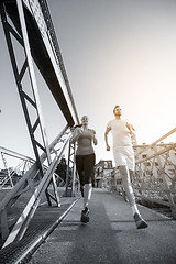 Image showing young couple jogging across the bridge in the city