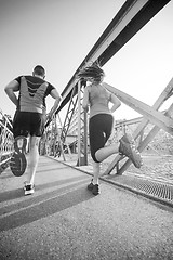 Image showing young couple jogging across the bridge in the city