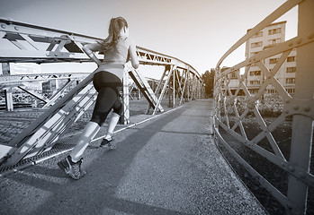 Image showing woman jogging across the bridge at sunny morning