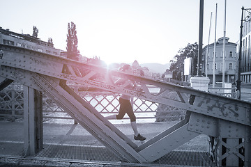 Image showing woman jogging across the bridge at sunny morning