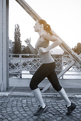 Image showing woman jogging across the bridge at sunny morning