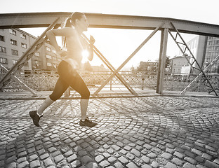 Image showing woman jogging across the bridge at sunny morning