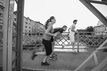 Image showing young couple jogging across the bridge in the city