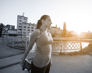 Image showing woman jogging across the bridge at sunny morning