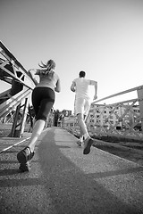 Image showing young couple jogging across the bridge in the city