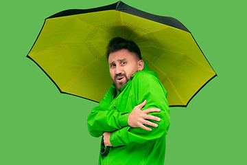 Image showing handsome bearded young man holding umbrella and looking at camera isolated on white