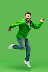 Image showing handsome bearded young man running isolated on green