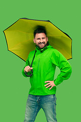 Image showing handsome bearded young man holding umbrella and looking at camera isolated on white