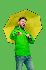 Image showing handsome bearded young man holding umbrella and looking at camera isolated on white