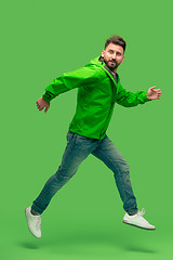 Image showing handsome bearded young man running isolated on green