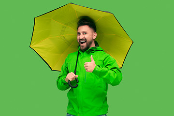 Image showing handsome bearded young man holding umbrella and looking at camera isolated on white