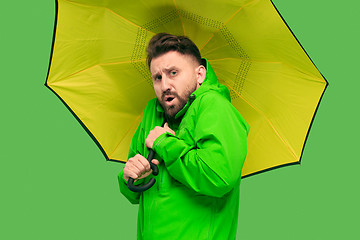Image showing handsome bearded young man holding umbrella and looking at camera isolated on white