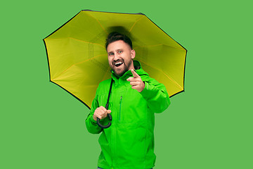 Image showing handsome bearded young man holding umbrella and looking at camera isolated on white