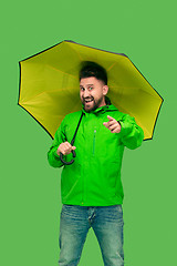 Image showing handsome bearded young man holding umbrella and looking at camera isolated on white