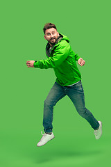Image showing handsome bearded young man running isolated on green