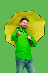 Image showing handsome bearded young man holding umbrella and looking at camera isolated on white