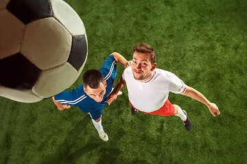 Image showing Football players tackling for the ball over green grass background