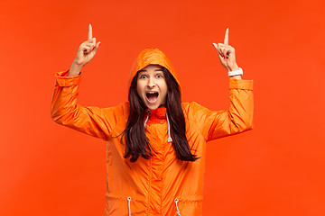 Image showing The young girl posing at studio in autumn jacket isolated on red