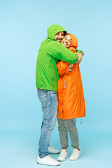 Image showing The young surprised couplel posing at studio in autumn jackets isolated on blue