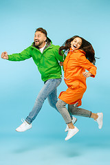 Image showing The young surprised couplel posing at studio in autumn jackets isolated on blue
