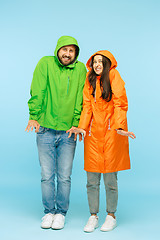 Image showing The young couplel posing at studio in autumn jackets isolated on blue