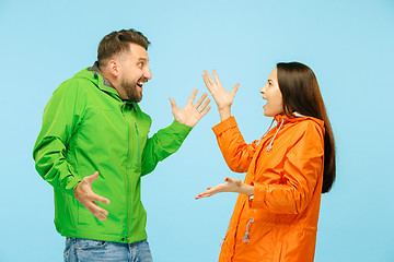 Image showing The young surprised couplel posing at studio in autumn jackets isolated on blue