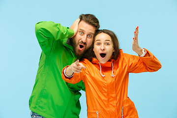 Image showing The young surprised couplel posing at studio in autumn jackets isolated on blue