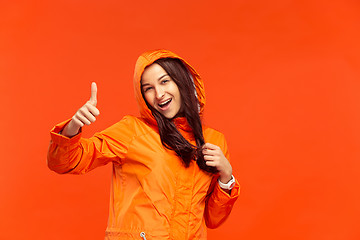 Image showing The young girl posing at studio in autumn jacket isolated on red