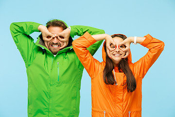 Image showing The young surprised couplel posing at studio in autumn jackets isolated on blue