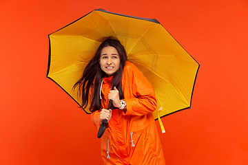 Image showing The young girl posing at studio in autumn jacket isolated on red