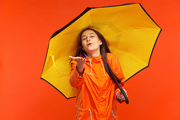 Image showing The young girl posing at studio in autumn jacket isolated on red