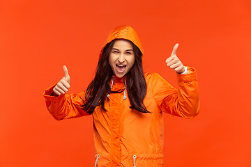 Image showing The young girl posing at studio in autumn jacket isolated on red