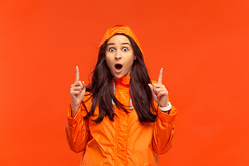 Image showing The young girl posing at studio in autumn jacket isolated on red