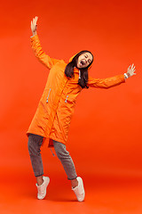 Image showing The young girl posing at studio in autumn jacket isolated on red