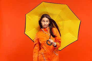 Image showing The young girl posing at studio in autumn jacket isolated on red