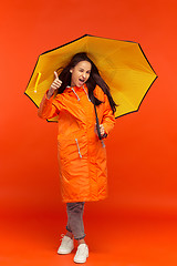 Image showing The young girl posing at studio in autumn jacket isolated on red