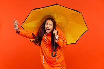 Image showing The young girl posing at studio in autumn jacket isolated on red