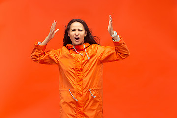 Image showing The young girl posing at studio in autumn jacket isolated on red