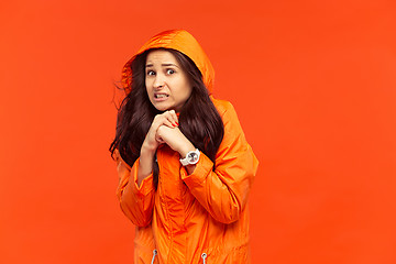 Image showing The young girl posing at studio in autumn jacket isolated on red