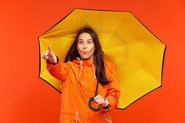 Image showing The young girl posing at studio in autumn jacket isolated on red