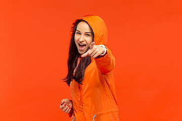 Image showing The young girl posing at studio in autumn jacket isolated on red