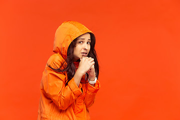 Image showing The young girl posing at studio in autumn jacket isolated on red