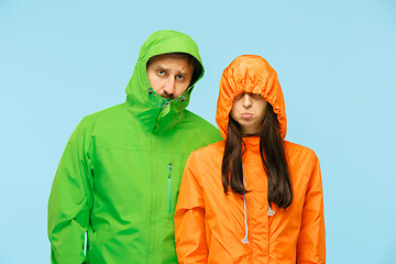 Image showing The young couplel posing at studio in autumn jackets isolated on blue