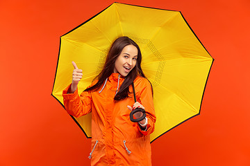 Image showing The young girl posing at studio in autumn jacket isolated on red