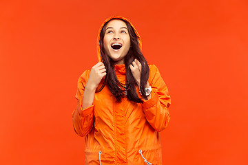 Image showing The young girl posing at studio in autumn jacket isolated on red