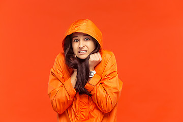 Image showing The young girl posing at studio in autumn jacket isolated on red