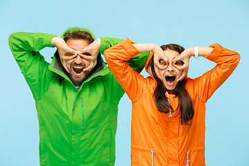 Image showing The young surprised couplel posing at studio in autumn jackets isolated on blue