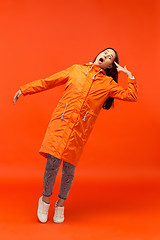 Image showing The young girl posing at studio in autumn jacket isolated on red