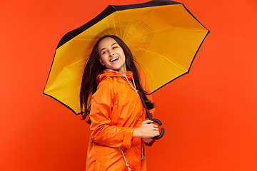 Image showing The young girl posing at studio in autumn jacket isolated on red