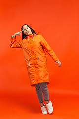 Image showing The young girl posing at studio in autumn jacket isolated on red